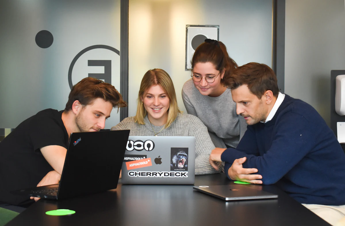 Equipe reunida em volta de um notebook discutindo um projeto